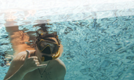 Taucher mit Taucherbrille in einem Schwimmbad gebärdet "ja".