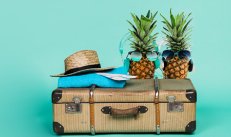 Koffer, Sonnenhut und Ananas