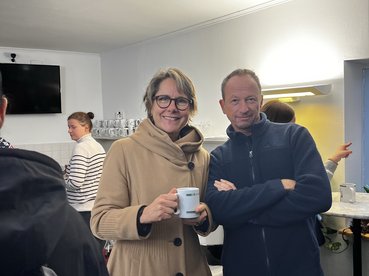 Marietta Adlbrecht steht in der equalizent-Cafeteria mit einer Tasse mit Punsch in der Hand. Neben ihr steht Christoph Salzmann mit verschränkten Armen.