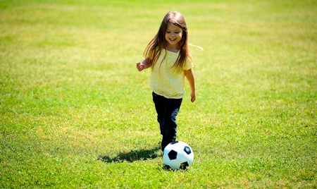 Mädchen auf Wiese spielt Fußball