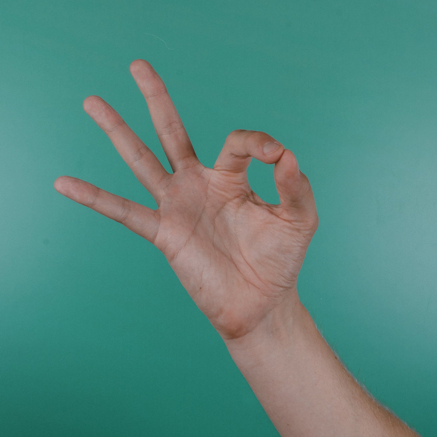 Eine Hand vor türkisem Hintergrund gebärdet "gut"
