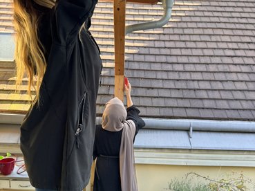 2 junge Frauen arbeiten an einer Holzpergola