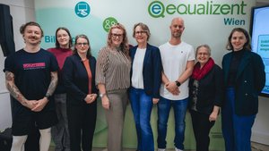 Acht Personen stehen vor einer Fotowand von equalizent. Es handelt sich um Experten und Fördergeber sowie um die GEschftsführung und den Schulungsmanager von equalizent.