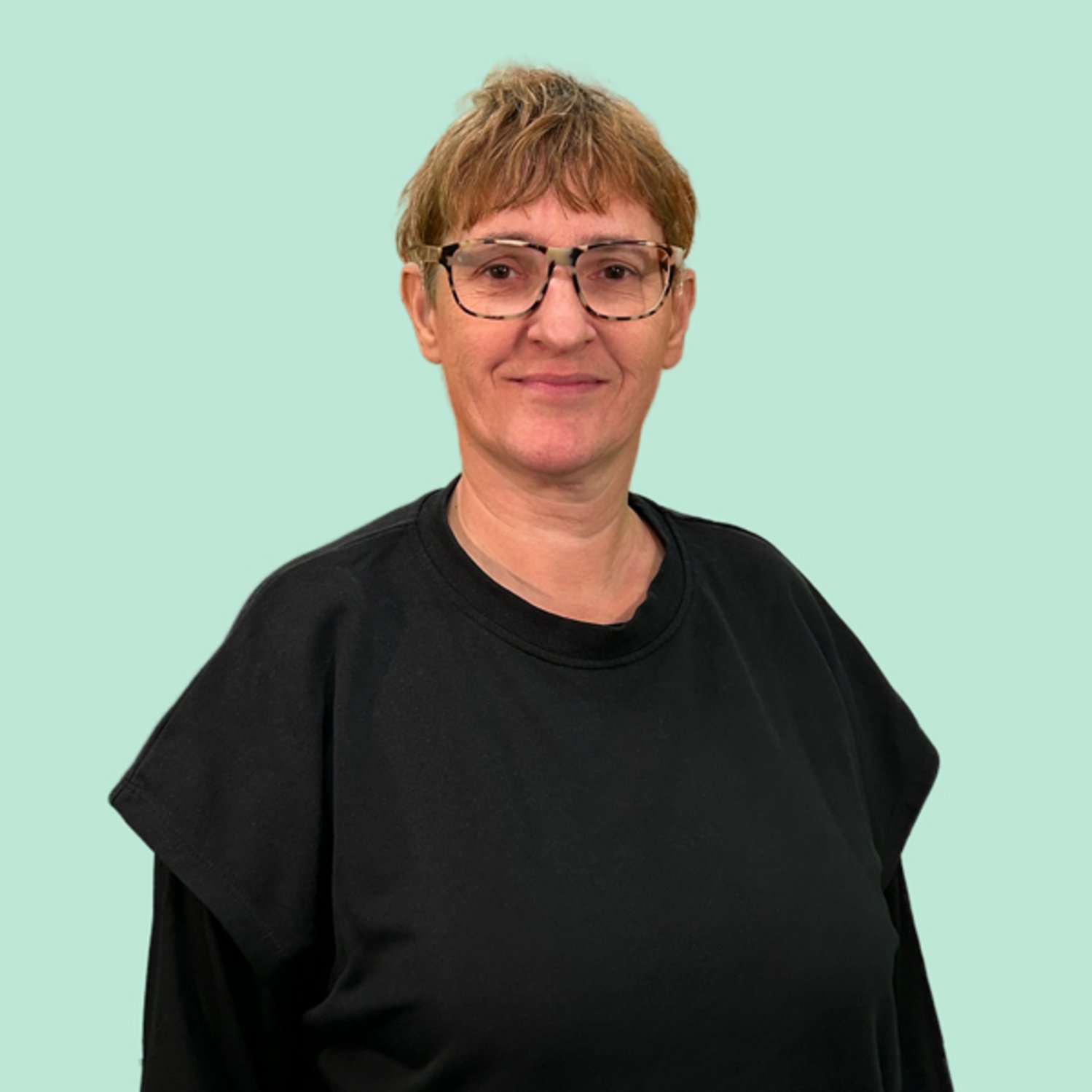 Frau mit kurzen blonden Haaren und Brille mit schwarzem Shirt bekleidet