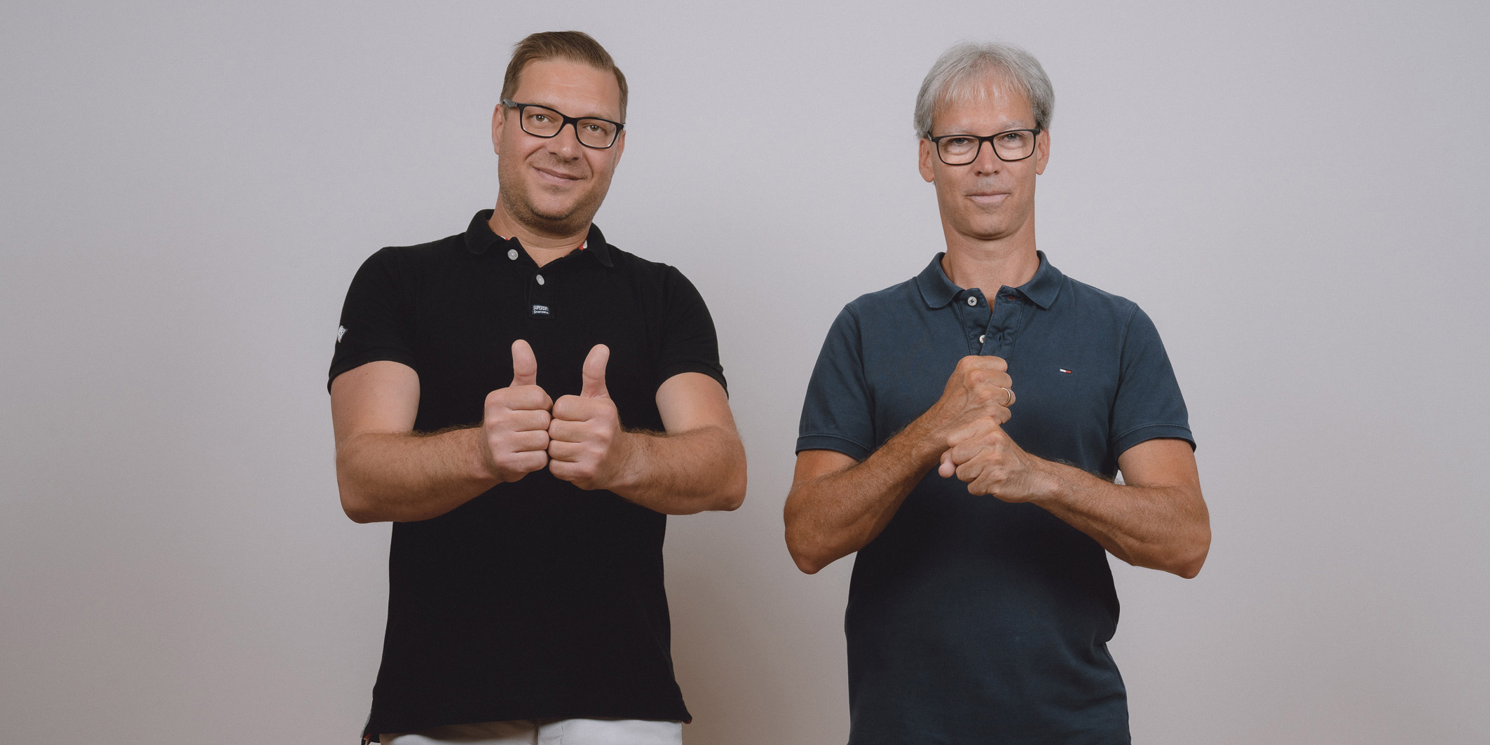 Zwei Männer stehen nebeneinander. Einer gebärdet "Partner", der andere "Arbeit".
