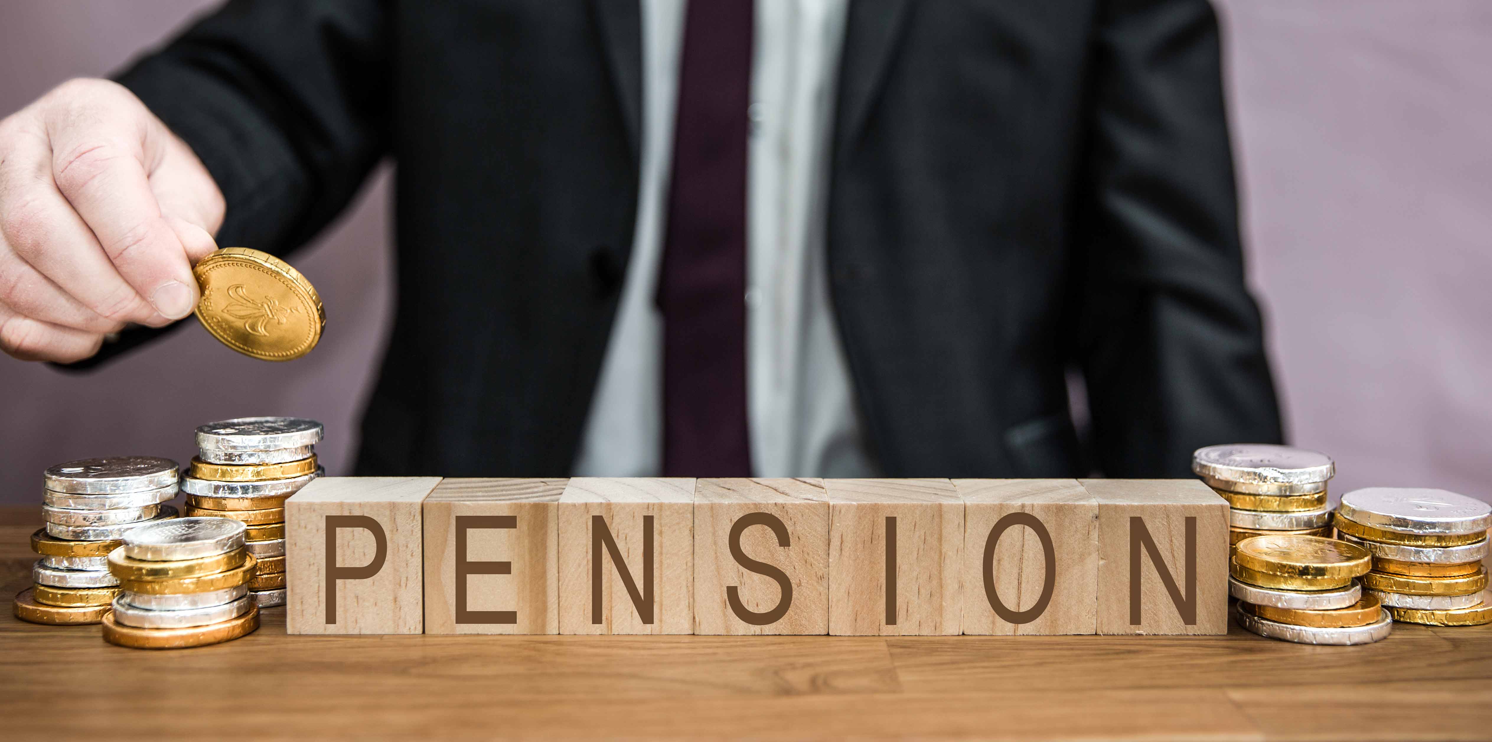 Mann im Anzug sortiert GEldmünzen, vor ihm bedinden sich kleine Würfel, auf denen das Wort "Pension" zu lesen ist.
