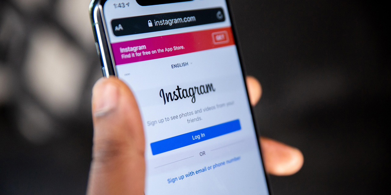 Eine Hand hält ein Smartphone auf dem die Startseite von Instagram zu sehen ist.